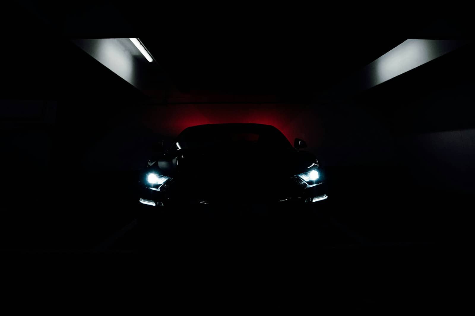 Car silhouette in a dark bay backlit by red light